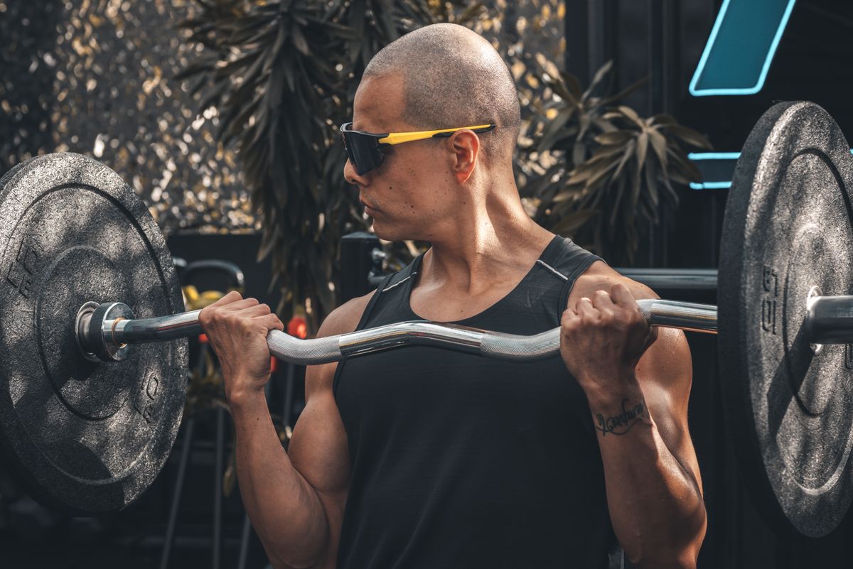 Man voert een biceps curl uit met een EZ-bar als isolatie oefening